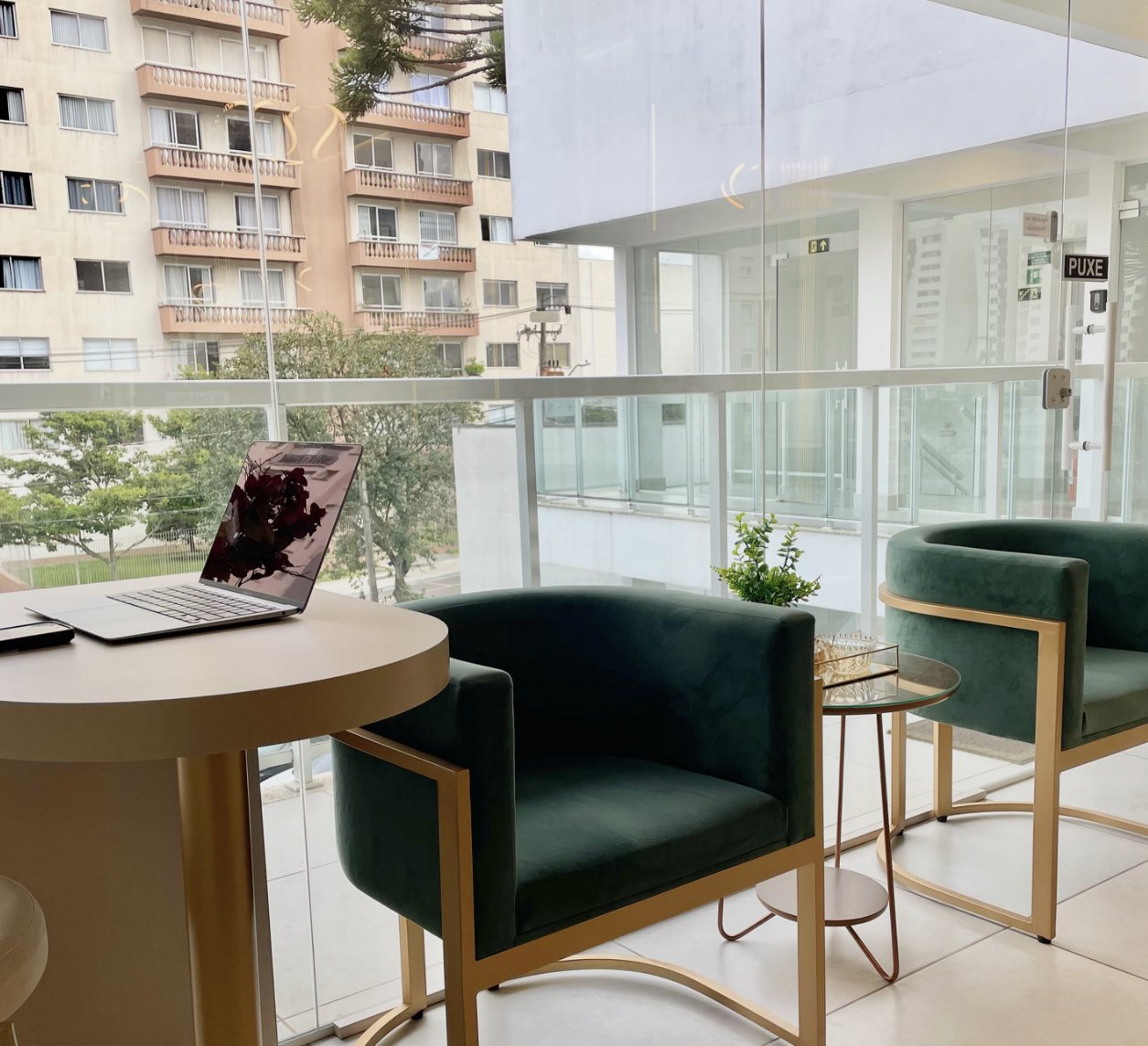 Recepção com poltronas de veludo verde ao lado da janela